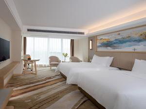 una camera d'albergo con due letti e una televisione di Vienna International Hotel South Gate of Shenzhen International Convention and Exhibition Center a Bao'an