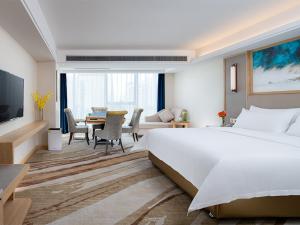 a bedroom with a large bed and a living room at Vienna International Hotel South Gate of Shenzhen International Convention and Exhibition Center in Bao'an