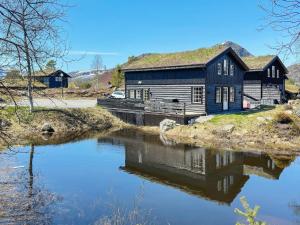 a blue house with a grass roof next to a river at Holiday home HOVDEN II in Hovden