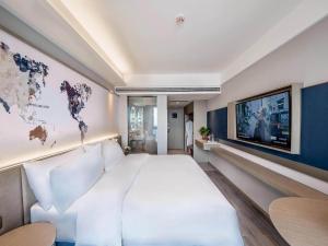 a bedroom with a large white bed and a world map on the wall at Kyriad Marvelous Hotel Qinhuangdao Nandaihe in Qinhuangdao +28 photos