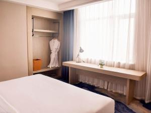 a bedroom with a bed and a window with a desk at Kyriad Marvelous Hotel Hengyang Changning in Changning