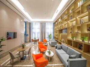 Kyriad Marvelous Hotel Qinhuangdao Nandaihe في تشنهوانغداو: مكتبة بها كراسي برتقالية وأرائك وطاولات