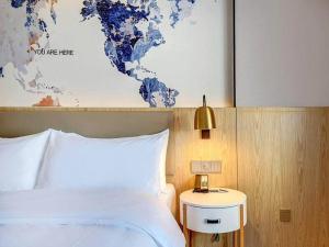 a bedroom with a bed and a map of the world at Kyriad Marvelous Hotel Haerbin West High-Speed Railway Station Wanda in Harbin