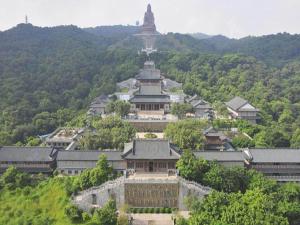 a large building with a tower on top of a mountain at Kyriad Marvelous Hotel Foshan Xiqiao Mountain Scenic Area Qiaoling Square in Nanhai