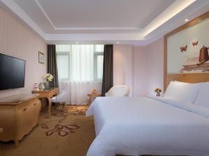 um quarto de hotel com uma cama grande e uma televisão em Vienna Hotel Huaidong Road Yuncheng em Yuncheng
