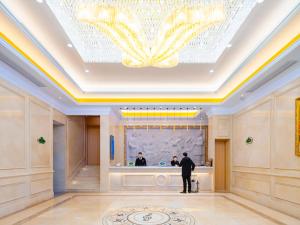 a man standing in front of a counter in a lobby at Vienna Hotel Lukou Airport in Jurong