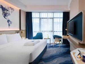 a hotel room with a large bed and a television at Kyriad Marvelous Hotel Shenzhen Longhua District Qinghu Subway Station in Tiantangwei