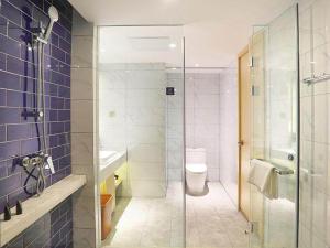 La salle de bains est pourvue de toilettes et d'une douche en verre. dans l'établissement Kyriad Marvelous Hotel Haerbin West High-Speed Railway Station Wanda, à Harbin