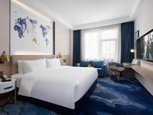 una camera d'albergo con un grande letto bianco e una scrivania di Kyriad Marvelous Hotel Shenzhen Baoan Gushu Metro Station a Bao'an
