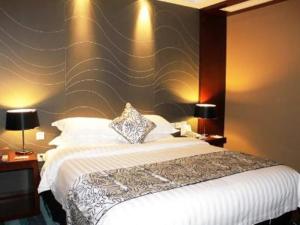a bedroom with a large bed and two lamps on tables at Metropolo Hotel Zhenjia Wanda Plaza Railway Station in Zhenjiang