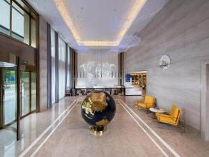 Kyriad Marvelous Hotel Hezhou Wanda Plaza في Hezhou: لوبي مع مزهرية كبيرة في وسط المبنى