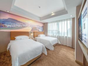 a hotel room with two beds and a painting on the wall at Vienna Hotel Qingyuan City Square Lianjiang Road Hotel in Qingyuan