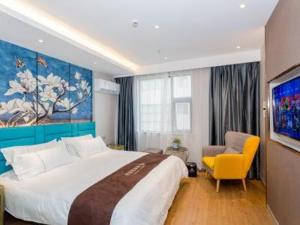 1 dormitorio con 1 cama grande y 1 silla amarilla en Magnotel YangZhou China Grand Canal Museum Wanda Plaza en Yangzhou