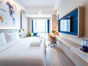 a hotel room with a large bed and a tv at Kyriad Hotel Shenzhen Pingdi Low Carbon City in Longgang