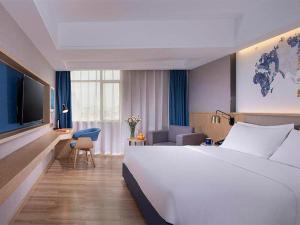 a hotel room with a large white bed and a television at Kyriad Marvelous Hotel Dongguan Changan Light Rail Station in Nongyucun