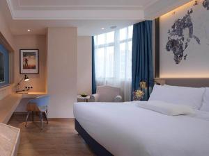 a bedroom with a large white bed and a desk at Kyriad Marvelous Hotel Heyuan Wanlong City in Heyuan