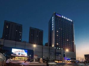 wysoki budynek z tabliczką w nocy w obiekcie Kyriad Marvelous Hotel Weihai Railway Station w mieście Weihai