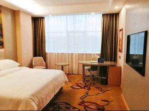 ein Hotelzimmer mit einem Bett, einem Tisch und einem TV in der Unterkunft Vienna International Hotel Zhejiang Wenzhou Ruian Tangxia in Ruian