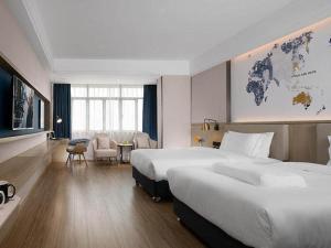 um quarto de hotel com duas camas e um mapa do mundo em Kyriad Marvelous Hotel Foshan Nanzhuang Taobo Avenue em Foshan