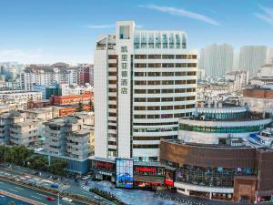 Ein hohes weißes Gebäude in einer Stadt mit Verkehr. in der Unterkunft Kyriad Marvelous Hotel Wuxi Zhongshan Road Chong'an Temple in Wuxi