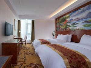 a hotel room with two beds and a painting on the wall at Vienna Hotel Jieyang Rongjiangxincheng Store in Jieyang