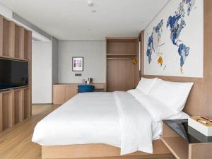 a bedroom with a large white bed and a tv at Kyriad Marvelous Hotel Daya Bay BYD Technology Park in Huizhou