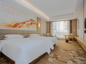 a hotel room with four beds and a painting on the wall at Vienna International Hotel Nanchang Qingshan Lake Wanda Plaza in Nanchang