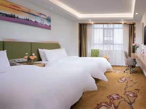 1 Schlafzimmer mit 2 großen weißen Betten und einem Fenster in der Unterkunft Vienna SanHao Hotels Yichun Gao'an Avenue in Gao'an