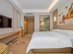 1 dormitorio con 1 cama blanca grande y TV de pantalla plana en Vienna International Hotel Nanchang Qingshan Lake Wanda Plaza, en Nanchang