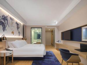 a bedroom with a large white bed and a flat screen tv at Kyriad Marvelous Hotel Yiyang Ziyang in Yiyang