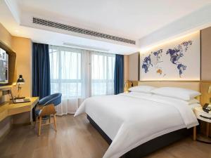 a hotel room with a large white bed and a desk at Kyriad Marvelous Hotel Henan Xinyang Pingqiao Plaza in Xinyang +36 photos