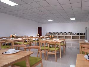 a dining room with wooden tables and green chairs at Vienna SanHao Hotels Yichun Gao'an Avenue in Gao'an