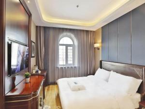 ein Schlafzimmer mit einem großen weißen Bett und einem Fenster in der Unterkunft Kyriad Marvelous Hotel Harbin Railway Station Central Avenue in Harbin
