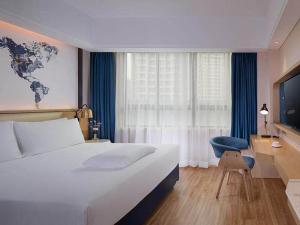 um quarto de hotel com uma cama grande e uma cadeira em Kyriad Marvelous Hotel Haikou Free Trade Zone em Haikou