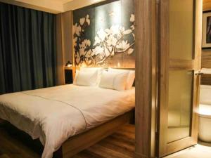 a bedroom with a bed with a painting on the wall at Magnolia Business Hotel Yangzhou Wanda Plaza Shunda Road in Yangzhou