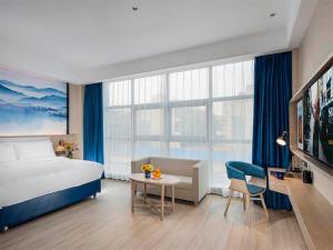 洛陽的住宿－凯里亚德酒店(洛阳龙门高铁站店)，酒店客房配有床、桌子和沙发。