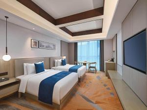 徐州市にあるGolden Tulip Xuzhou Huaihaiのベッド2台、薄型テレビが備わるホテルルームです。