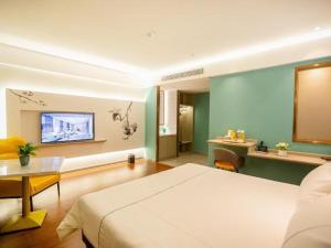 a hotel room with a bed and a table and a television at Magnotel Hotel Yangzhou Jinghua Wangyue Road in Yangzhou