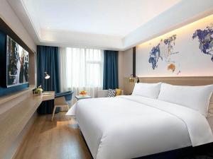 a hotel room with a large white bed and a desk at Kyriad Marvelous Hotel Changde Pedestrian Street in Changde