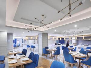a restaurant with blue chairs and tables and a person at Kyriad Marvelous Hotel Yiyang Ziyang in Yiyang