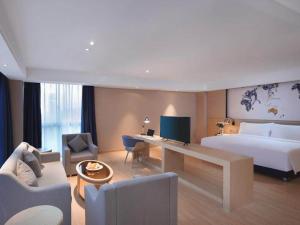 una camera d'albergo con letto e scrivania di Kyriad Marvelous Hotel Suzhou Wujiang People Square a Suzhou
