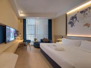 a hotel room with a large bed and a couch at Kyriad Marvelous Hotel Shanghai International Tourist Resort Pudong Airport in Nanhui