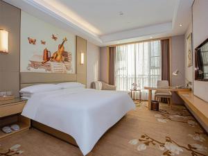 una camera con un grande letto bianco e una scrivania di Vienna International Hotel Nanchang Qingshan Lake Wanda Plaza a Nanchang