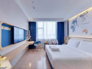 Cette chambre comprend un grand lit et une télévision. dans l'établissement Kyriad Marvelous Hotel Guangzhou Baiyun International Airport, à Canton
