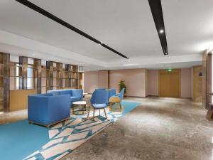 a waiting room with blue chairs and tables and shelves at Kyriad Jinjiang Hotel in Jinjiang