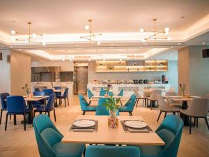 a restaurant with tables and chairs and a kitchen at Kyriad Marvelous Hotel Foshan Xiqiao Mountain Scenic Area Qiaoling Square in Nanhai