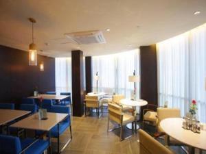- une salle à manger avec des tables, des chaises et des fenêtres dans l'établissement Jinjiang Inn Yangzhou Gaoyou East Haichao Road, à Gaoyou
