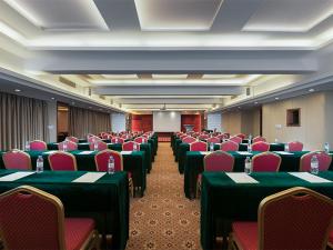 a conference room with green tables and red chairs at Vienna Hotel Qingyuan City Square Lianjiang Road Hotel in Qingyuan