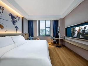 a hotel room with a bed and a flat screen tv at Kyriad Marvelous Hotel Chaozhou Fortune Central in Chaozhou