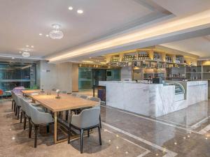 a dining room with a table and chairs and a kitchen at Kyriad Hotel Shenzhen Pingdi Low Carbon City in Longgang